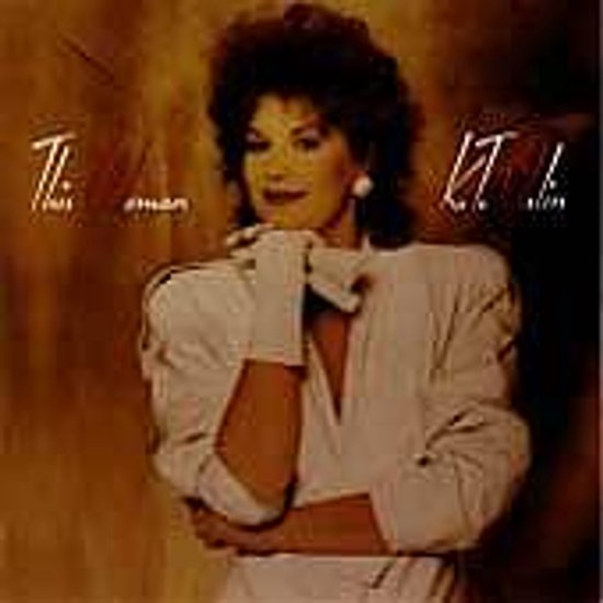 K.T. Oslin in een wit jasje met handschoenen, albumhoes This Woman met warme bruine achtergrond.