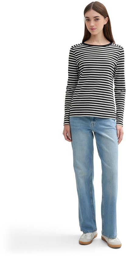 Model met lange mouwen zwart-wit gestreept T-shirt met ronde hals en lichtblauwe jeans.