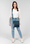 Model met donkergroene schoudertas, jeans en witte trui.