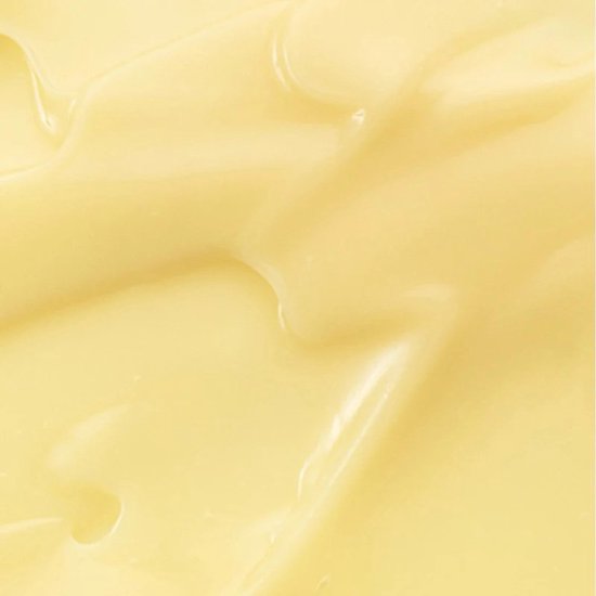 Een close-up textuur van een dikke, romige, lichtgele crème met golvende lijnen en glans.