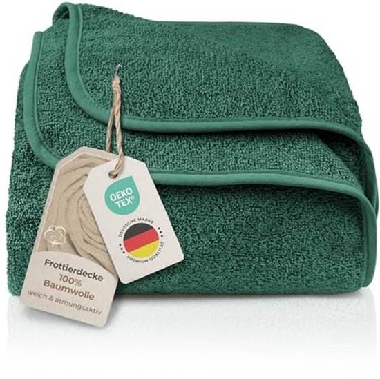 Opgevouwen donkergroene badstof katoenen deken met labels over Oeko-Tex en 100% katoen.
