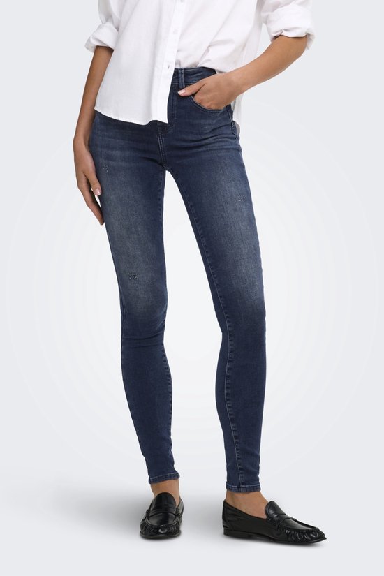 Vooraanzicht van een blauwe push-up skinny jeans met witte blouse en zwarte loafers.