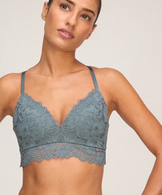 Model draagt een blauwe Hunkemöller bralette met een V-hals en gedetailleerd bloemenkant.