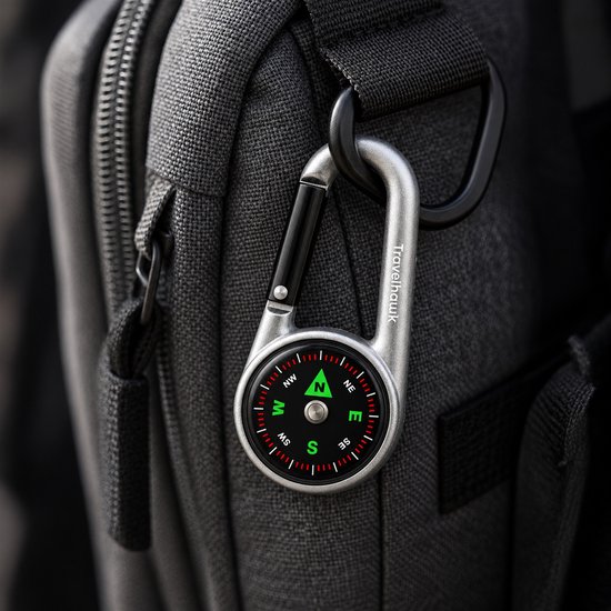 Zilverkleurige Travelhawk karabijnhaak met kompas bevestigd aan een grijze tas.