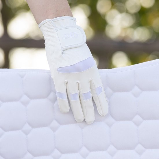 Witte ruiterhandschoen met QHP-logo op de pols, rustend op een wit zadeldek.