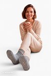 Vrouw met een kopje, zittend, met pantoffelsokken met noppen.