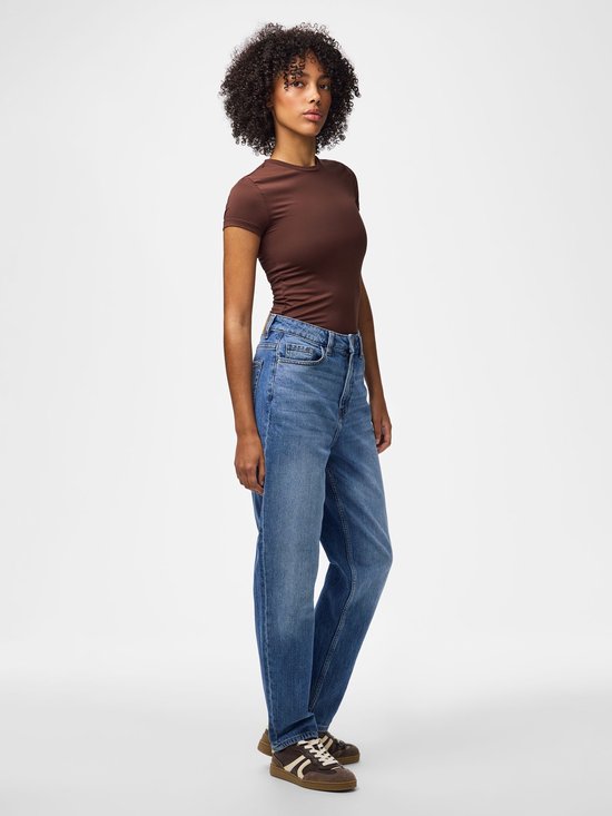 Model van opzij gezien in een blauwe jeans met rechte pijpen en hoge taille, gecombineerd met een bruin shirt.