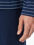 Detail van de mouw van een marineblauw gestreept T-shirt gecombineerd met een effen marineblauwe broek.
