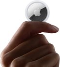 Hand die een ronde Apple AirTag vasthoudt tegen een lichte achtergrond.