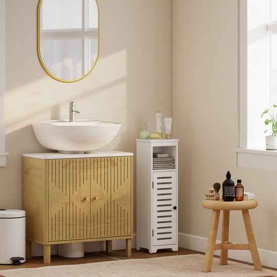 Witte smalle badkamerkast met lamellendeur naast een houten badkamermeubel met wastafel.