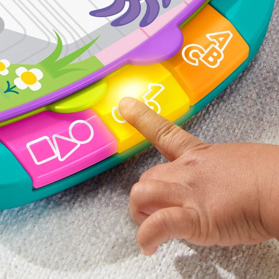Een kinderhand drukt op gele, oranje en roze toetsen met vormen, letters en cijfers op een felgekleurd speelgoedboek.