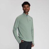 Man met krullend haar in mintgroene longsleeve met halve rits, één hand in de zak.