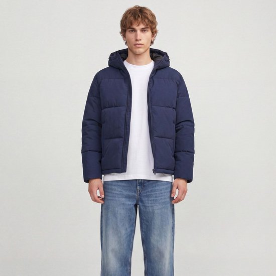 Model draagt een donkerblauwe pufferjack, open rits, met witte T-shirt.