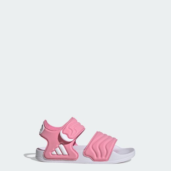 Roze Adilette kindersandaal op witte zool met klittenbandsluiting en Adidas logo.