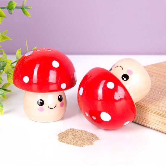 Twee keramische paddenstoelen zout- en pepervaatjes, één staat recht met rode hoed met witte stippen, de ander ligt met hoed naar voren.