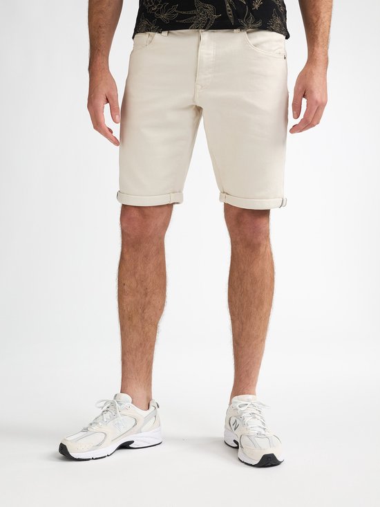 Man in beige shorts en witte sneakers.