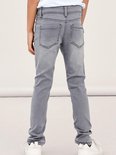 Achterkant van een grijze, aansluitende jeans met opgestikte achterzakken en zwarte stiksels.