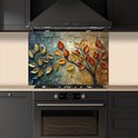 Keukenspatscherm met abstracte boom, gouden en oranje bladeren. Geplaatst boven een zwarte inductiekookplaat en oven.