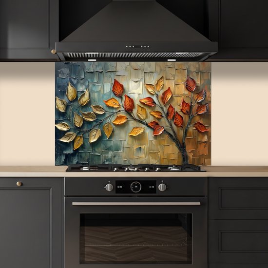 Keukenspatscherm met abstracte boom, gouden en oranje bladeren. Geplaatst boven een zwarte inductiekookplaat en oven.