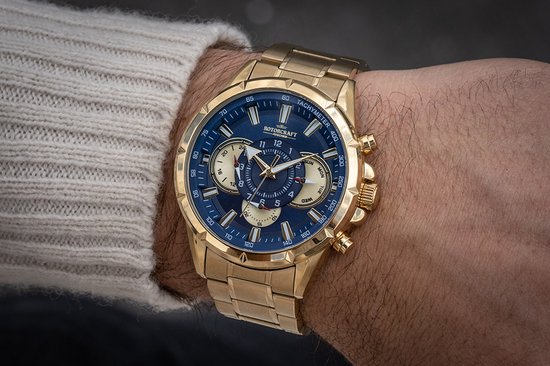 Gouden horloge met blauwe wijzerplaat en gouden band gedragen om een mannenpols.
