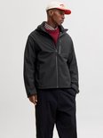 Man met zwarte softshell jas, rood vest, beige pet.