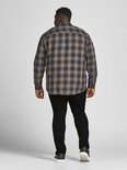 Achterkant van een man in een geruite blouse en zwarte jeans, met witte sneakers.