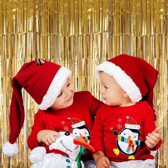 Twee kinderen in kerstmutsen en truien met pinguïnprint.