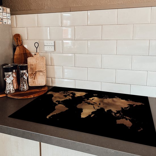 Zwarte inductiebeschermer met wereldkaartprint op een aanrecht naast een inductiekookplaat.