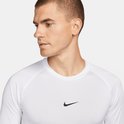 Close-up van een man die een wit Nike Pro longsleeve shirt draagt met een zwart Nike logo op de borst.