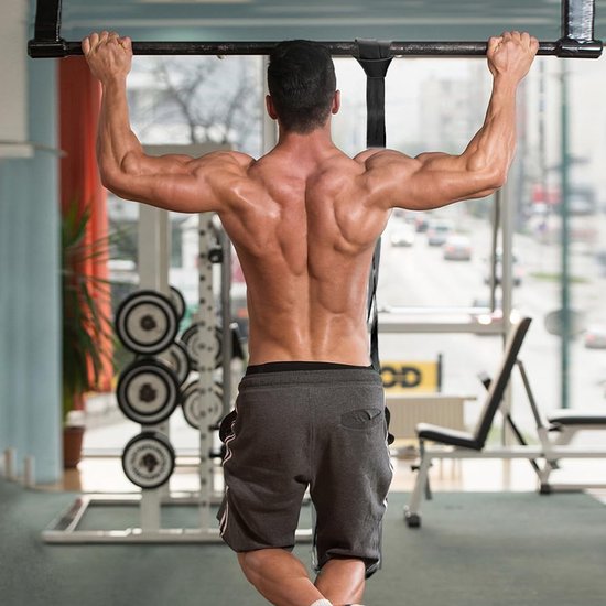 Homme au dos musclé effectuant une traction à une barre dans une salle de sport.
