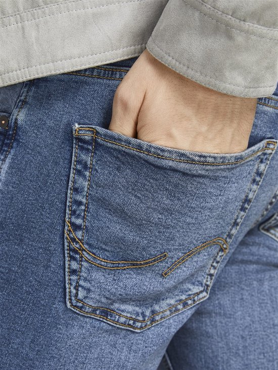 Achterzak van een lichtblauwe spijkerbroek met oranje stiksels.