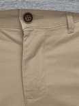 Detail van de gulp van een beige chino broek met knoop.
