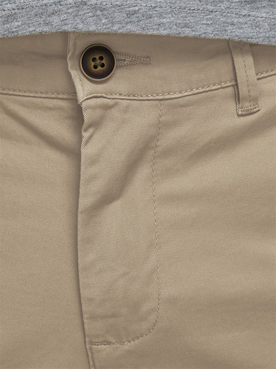 Detail van de gulp van een beige chino broek met knoop.