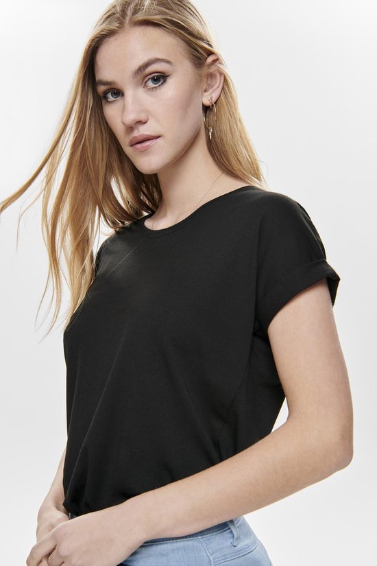Model in zwart T-shirt met opgerolde mouwen en lichte jeans.