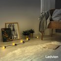 Een reeks van helder verlichte E27 lampen aan een zwarte kabel, geplaatst op een witte shaggy vloerkleed.