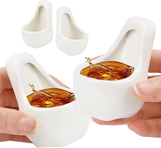 Drie witte keramische urinoir-vormige borrelglaasjes, twee gevuld met amberkleurige drank, vastgehouden door handen.