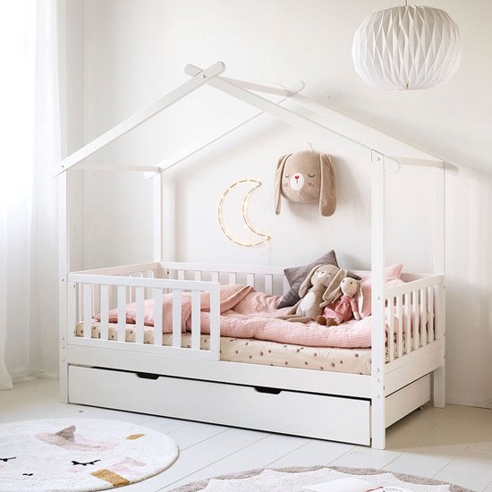 Wit huisbed met roze hemel, beddengoed, knuffels en een maanlamp.