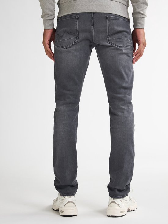 Detail van de achterkant van grijze slim fit jeans met merklabel.
