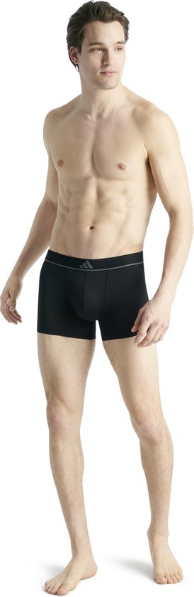 Man in zwarte Adidas boxer, staand, met grijze tailleband en logo.
