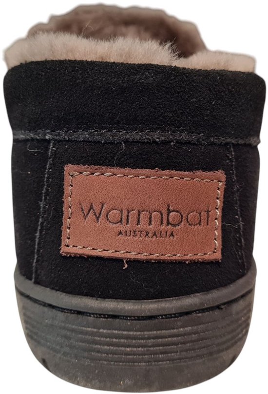 Achterkant van zwarte suède sloffen met een bruin label 'Warmbat Australia' en beige vacht.
