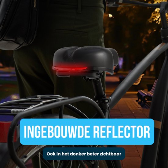 Een persoon op een fiets met een zwart zadel met een ingebouwde rode reflector die oplicht in het donker. De tekst "INGEBOUWDE REFLECTOR" staat op een blauw vlak.