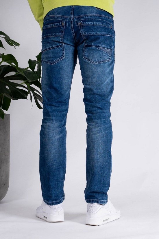 Man met de rug naar de camera, draagt een blauwe spijkerbroek met stonewash-effect.
