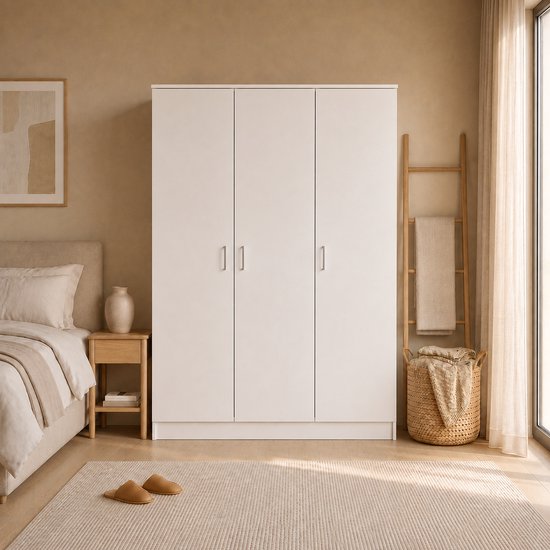 Gesloten witte driedeurskast in een slaapkamer, naast een bed.