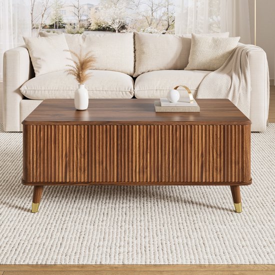 Table basse en noyer avec motif côtelé et pieds dorés, placée sur un tapis dans un salon.