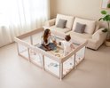 Beige grondbox met een vrouw en baby in een woonkamer. De baby staat en kijkt naar de vrouw.