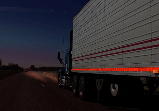 Blauwe vrachtwagen met witte trailer, voorzien van oranje reflecterende contourmarkering op de zijkant.