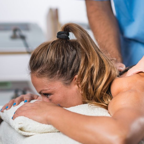 Massage van de rug van een vrouw met paardenstaart.