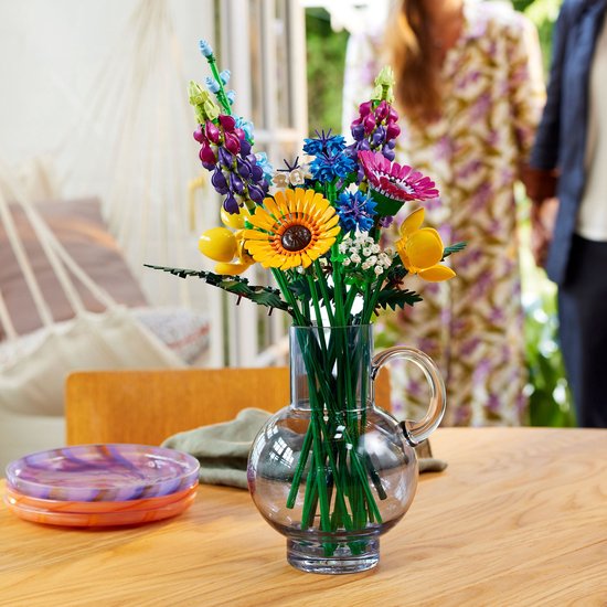 Een boeket van Lego-bloemen in een glazen vaas op een houten tafel.