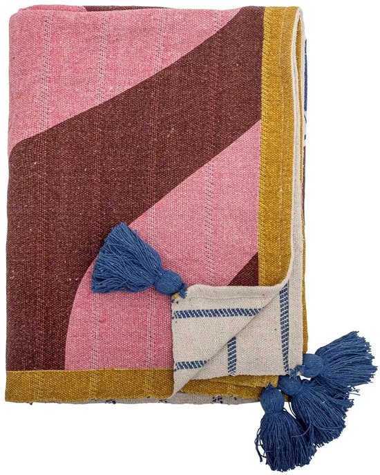 Gevouwen plaid met roze, bruine en gele strepen en geometrische vormen. Twee blauwe kwastjes aan de zoom.