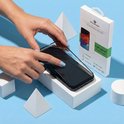Mains plaçant un protecteur d'écran Solidenz sur un smartphone noir. Emballage à côté du téléphone.